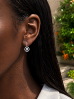 Load image into Gallery viewer, Close-up of a woman wearing a white gold natural diamond drop earring with a circular double-halo design and diamond-covered hook.