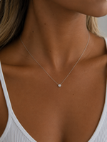 Load image into Gallery viewer, White gold necklace with a natural round diamond in a bezel setting, modeled on a woman’s neckline with a fine chain.