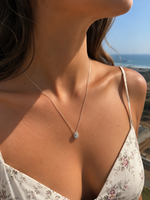 Load image into Gallery viewer, Woman wearing a round halo lab-grown diamond pendant necklace in yellow gold, front view on the neck