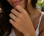 Load image into Gallery viewer, Round solitaire natural diamond ring with pavé side diamonds worn on a woman’s hand.
