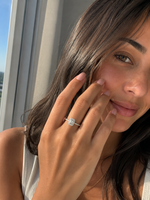 Load image into Gallery viewer, Emerald halo lab-grown diamond engagement ring on a woman’s hand in a natural lifestyle portrait, featuring a delicate pavé band and elegant halo setting.