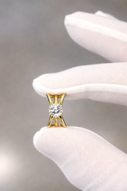 round cut diamond split shank engagement ring held by white glove on gray background