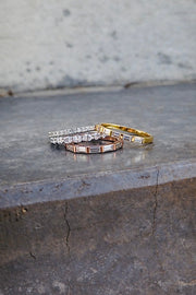 half eternity baguette diamond rings in yellow and rose gold with white gold oval and round diamond bands on gray concrete background