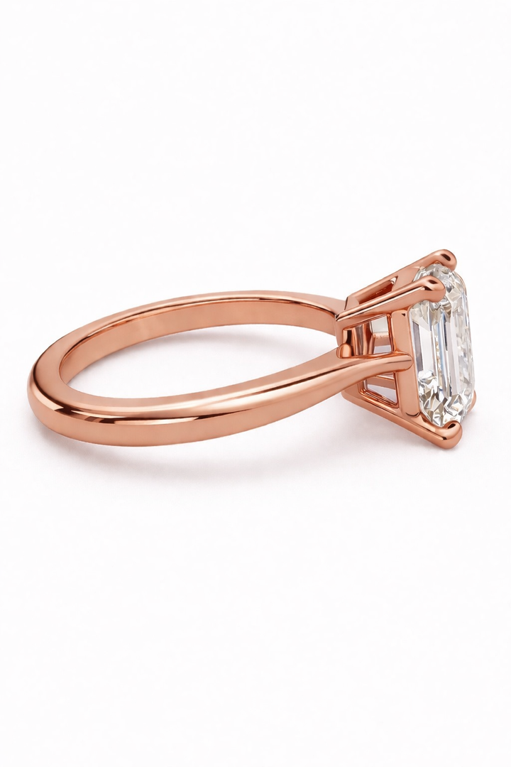 Rose gold emerald-cut solitaire natural diamond ring shown from the side.