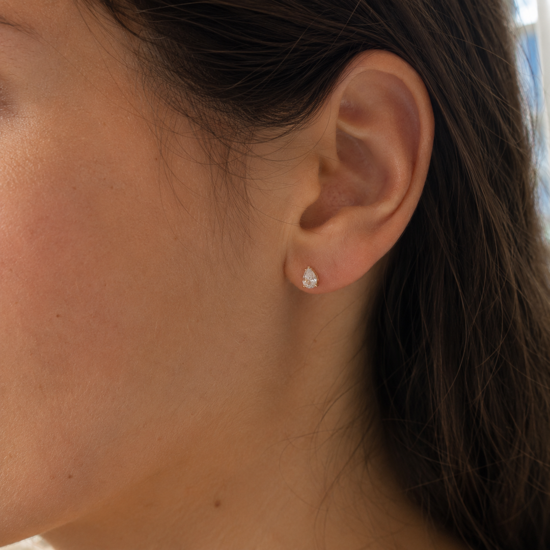 Woman wearing pear-cut lab-grown diamond stud earrings.