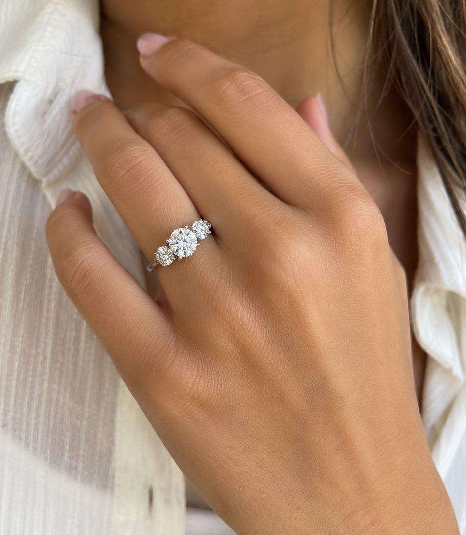 Three-stone round lab-grown diamond ring worn on hand, classic three-stone design in gold