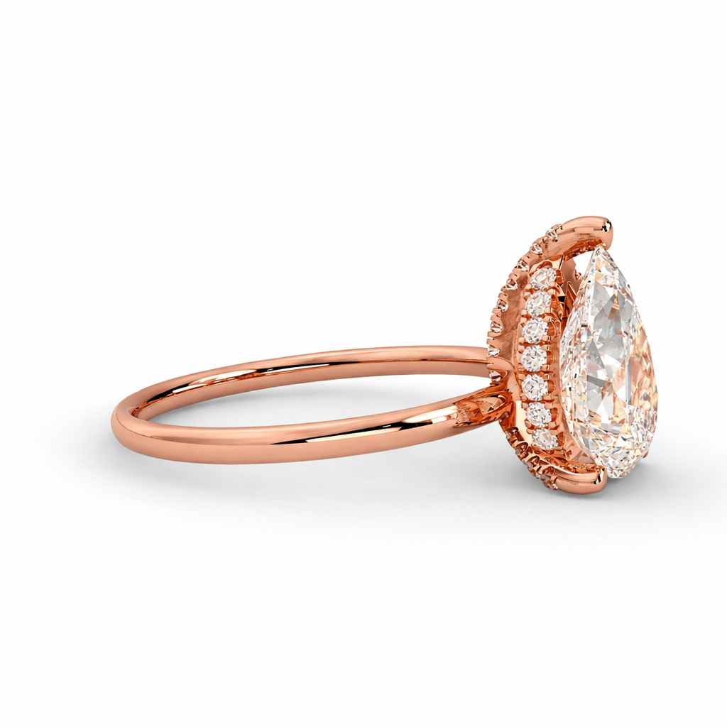 Side view of a lab grown pear cut diamond hidden halo engagement ring in 18K rose gold on a white background