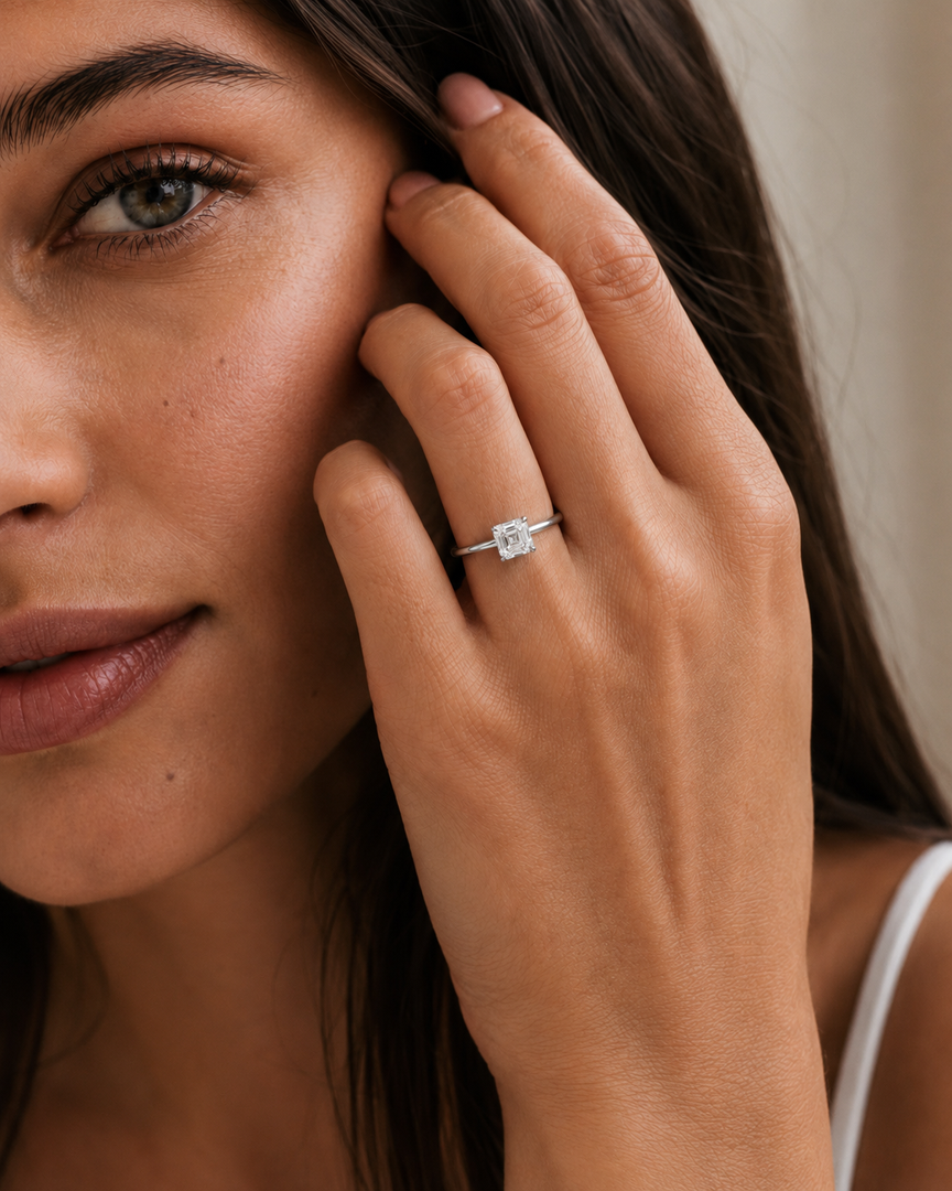 Asscher cut solitaire natural diamond ring worn on a woman’s hand.