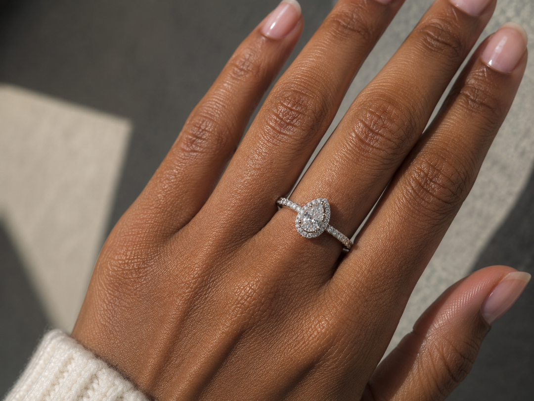 Lab-grown pear halo diamond ring in 14K white gold worn on a woman’s hand with a pear-shaped center diamond and halo.