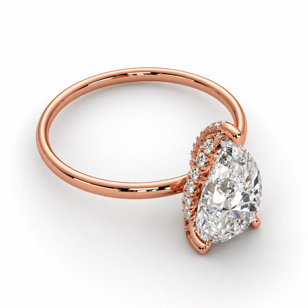     Side view of a pear solitaire natural diamond hidden halo engagement ring in 14K rose gold on a white background