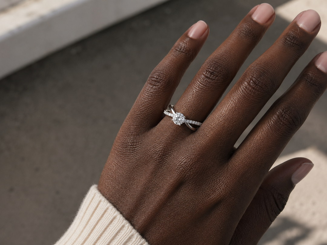     Woman wearing a white gold X-shank round natural diamond engagement ring with a pavé split band on her finger.
