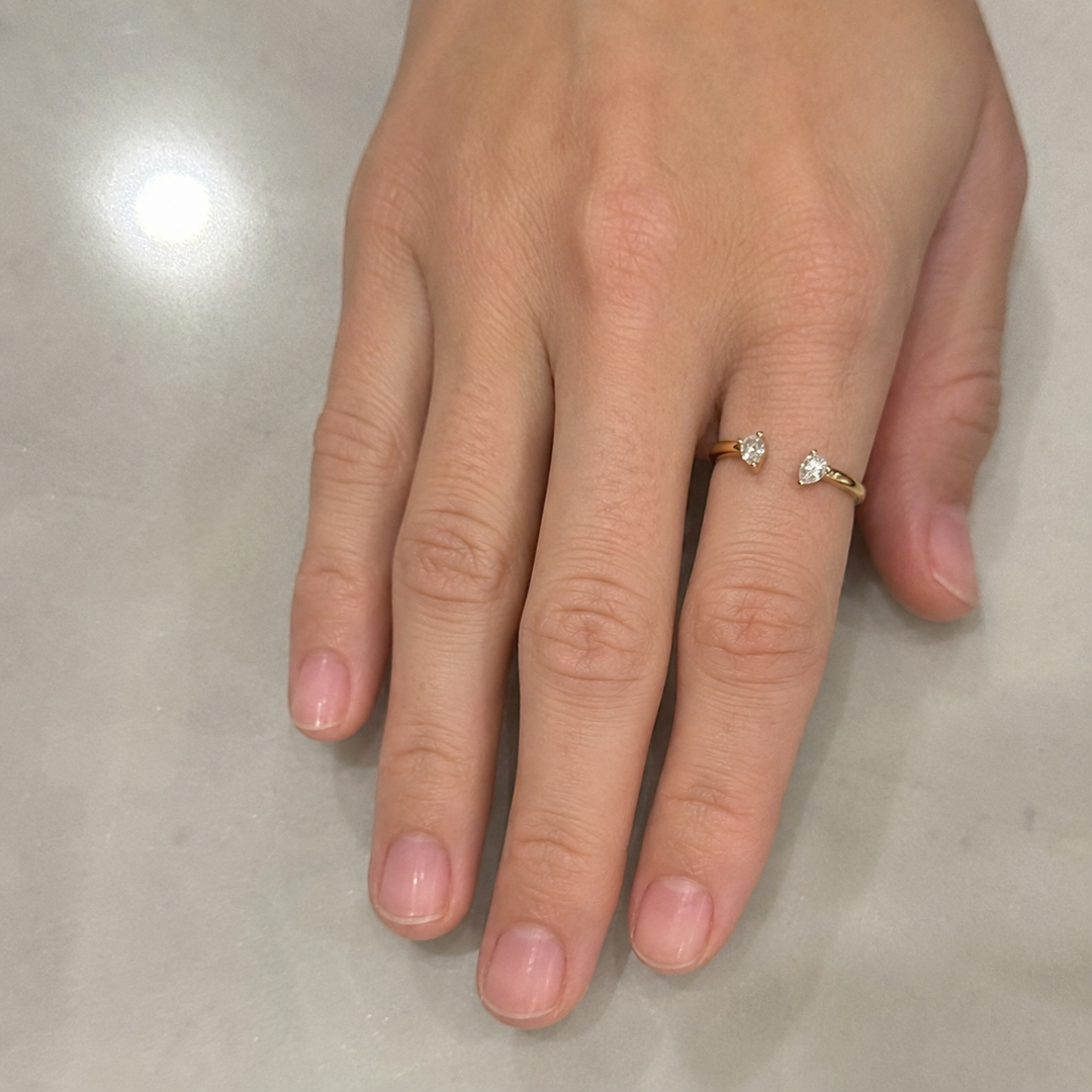 Woman wearing an open pear-cut natural diamond ring on her finger.