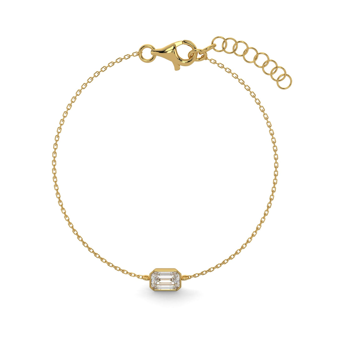     Emerald-cut natural diamond bezel bracelet in yellow gold on a white background.
