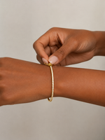 Load image into Gallery viewer, Close-Up of a Woman Wearing a Natural Diamond Yellow Gold Bangle Bracelet with Round Pavé Diamonds and a Sleek Hinged Style