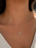 Load image into Gallery viewer,     Natural oval diamond pendant necklace in yellow gold, modeled on a woman’s neck with a fine cable chain.