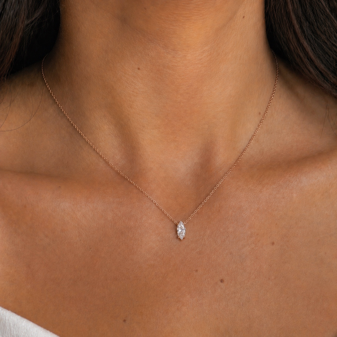 Woman wearing a marquise natural diamond solitaire pendant necklace in 14K rose gold on a fine cable chain with a minimalist everyday look.