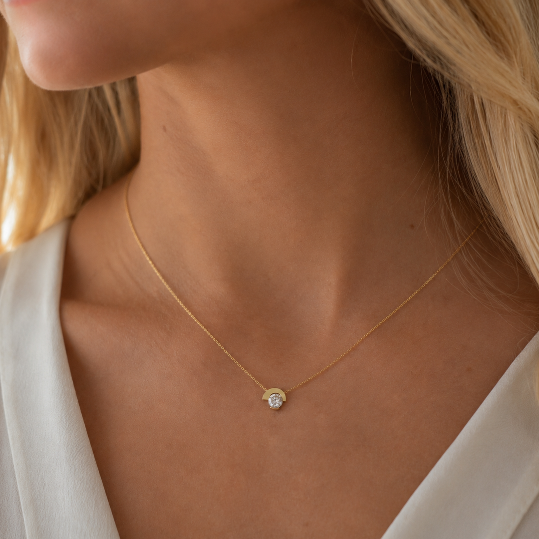 Asymmetric round lab-grown diamond pendant necklace in yellow gold shown on a woman’s neck.
