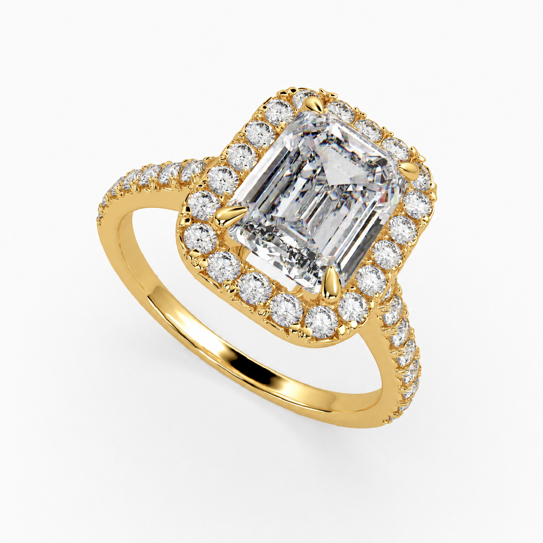 Natural emerald-cut diamond halo ring in yellow gold, three-quarter top view, with round diamond halo and pavé side stones