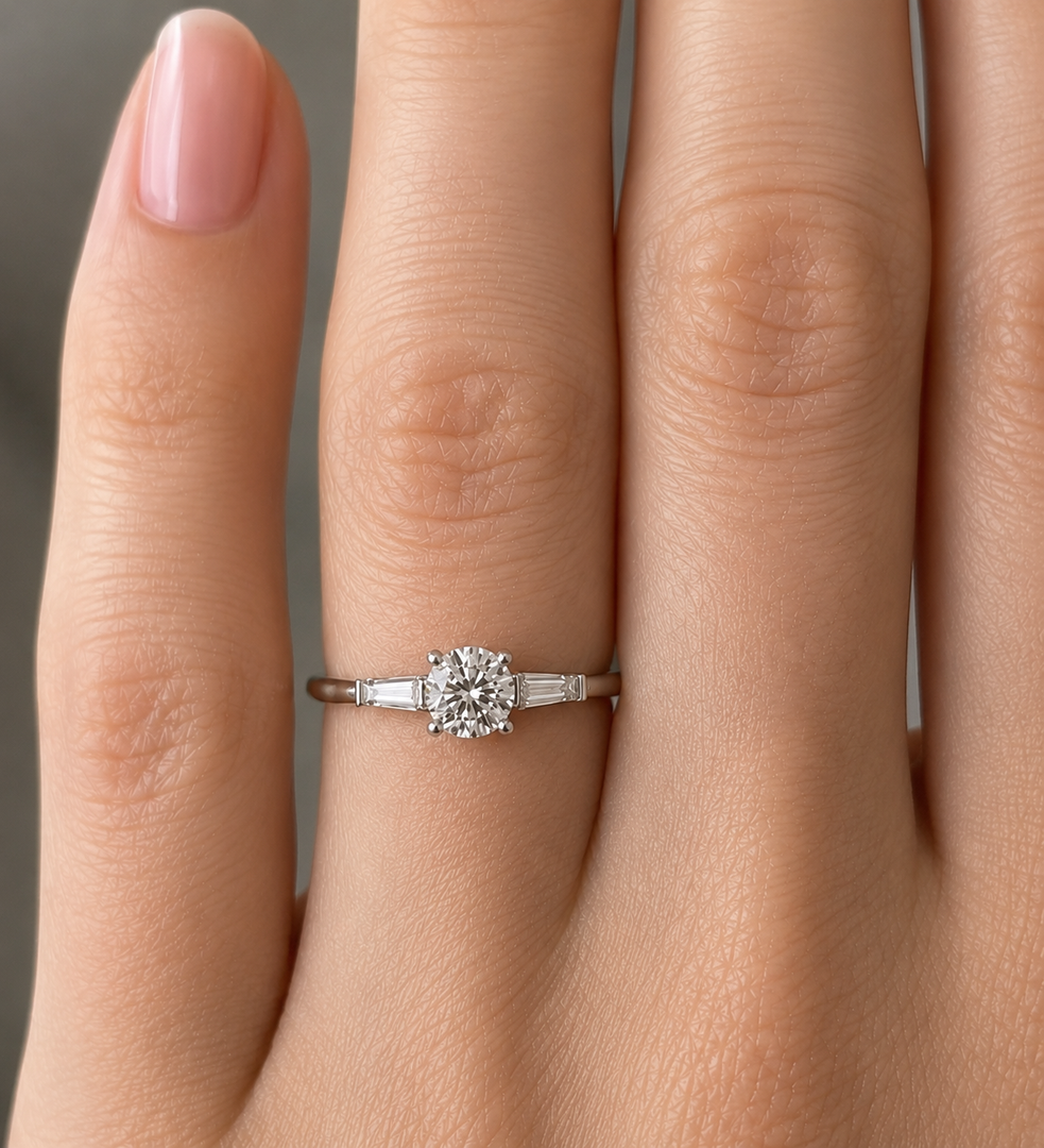 Three stone lab grown diamond engagement ring worn on hand, round center with tapered baguette sides