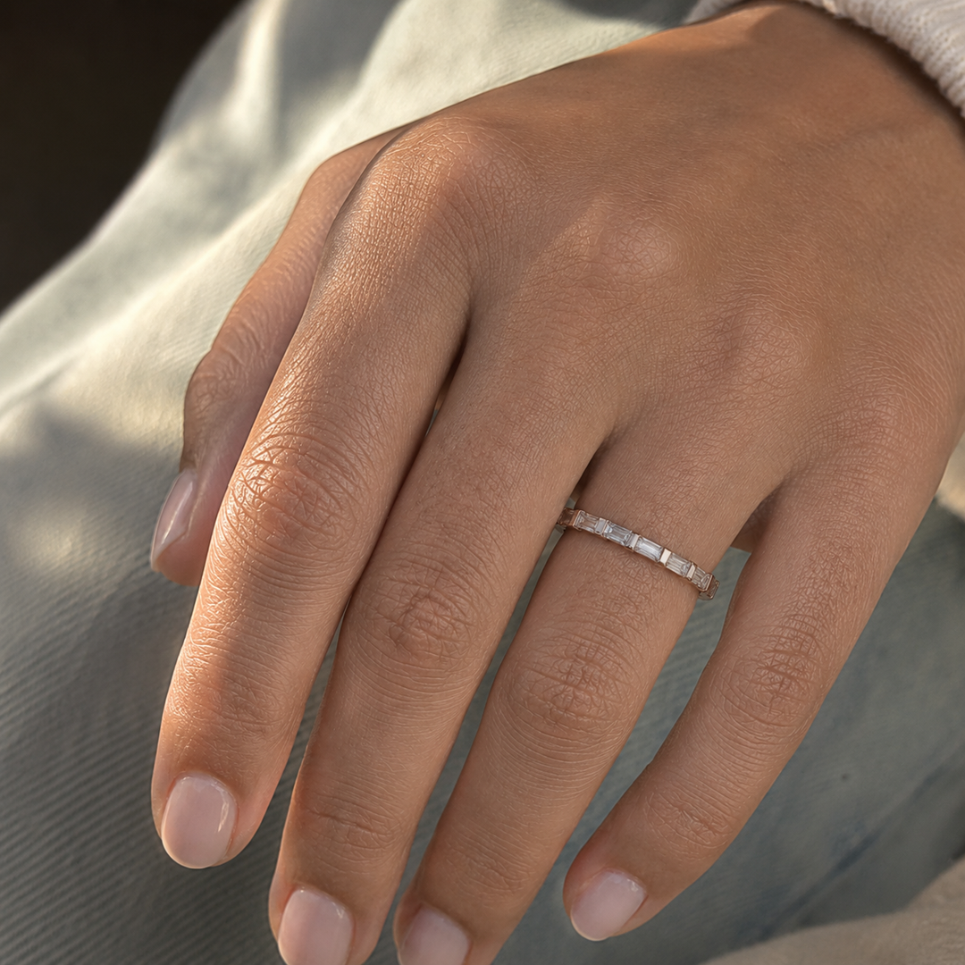 Horizontal baguette lab-grown diamond half eternity band worn on a woman’s hand.