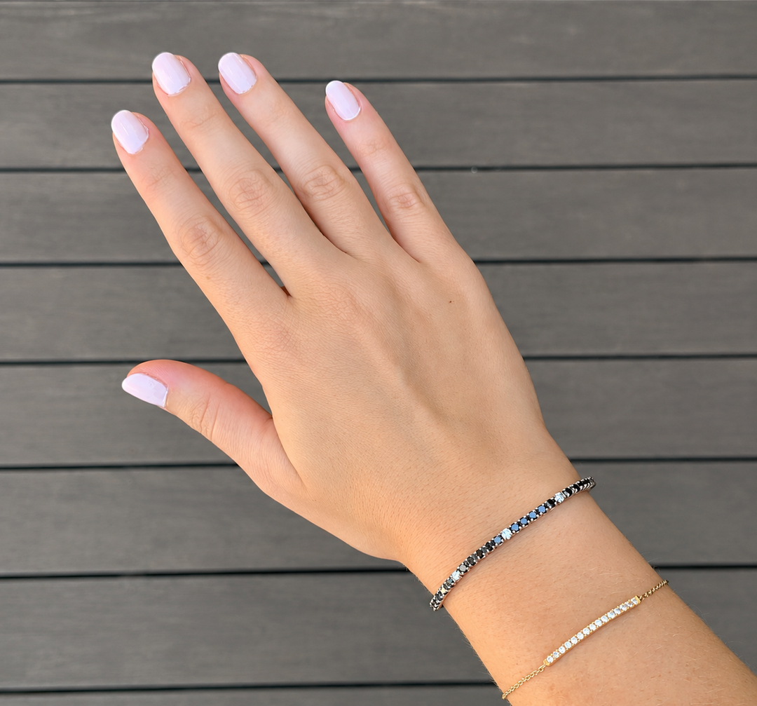 Lab-Grown Black & White Diamond Tennis Bracelet in White Gold on a Woman’s Wrist, Featuring Alternating Round Black and White Diamonds in a Classic Tennis Bracelet Design.