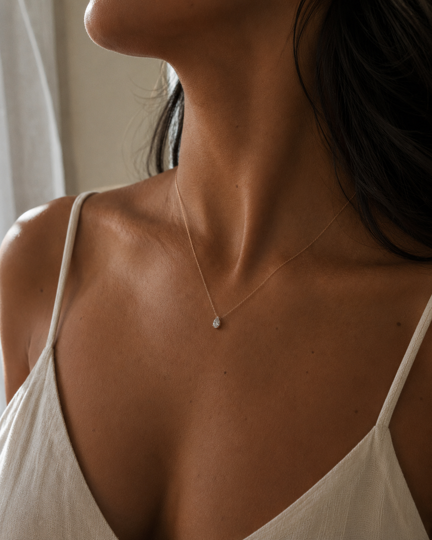Natural pear-cut diamond pendant necklace in rose gold, worn by a woman and centered at the neckline