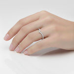Load image into Gallery viewer, Side view of a three-stone lab-grown diamond engagement ring with round center diamond and tapered side stones on hand
