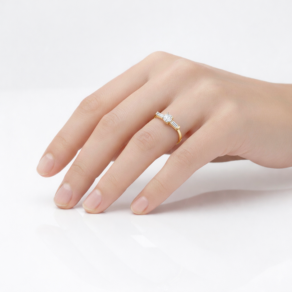 Three stone lab grown diamond engagement ring worn on hand, round center with tapered baguette sides