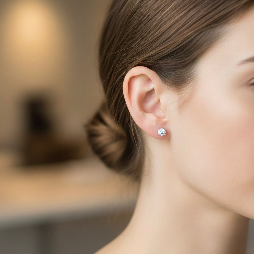 Round natural diamond stud earring worn on ear, classic solitaire setting with a single brilliant-cut diamond, minimalist fine jewelry close-up.