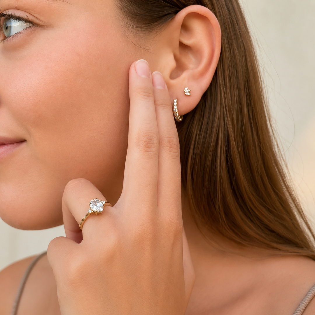     Three Stone Oval Natural Diamond Ring with Round Side Stones in Yellow Gold Worn on Hand