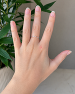 Load image into Gallery viewer, Side view of a three-stone lab-grown diamond engagement ring with round center diamond and tapered side stones on hand