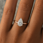 Load image into Gallery viewer, Pear solitaire natural diamond hidden halo engagement ring worn on a hand in 14K rose gold