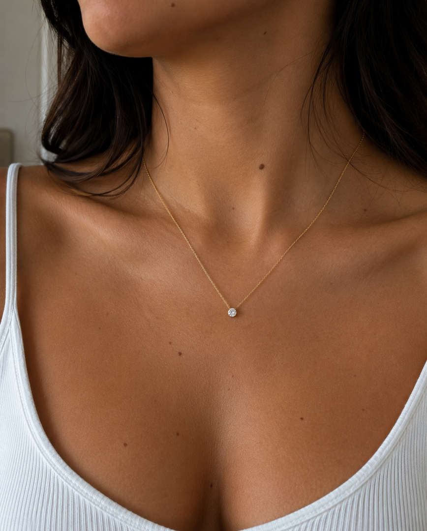 Woman Wearing a Round Natural Diamond Solitaire Necklace in 14K Yellow Gold with a Round Brilliant Diamond in a Classic Four-Prong Setting on a Fine Yellow Gold Chain