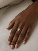 Load image into Gallery viewer, Woman wearing a white gold lab-grown oval three stone diamond ring with pear side diamonds on her hand