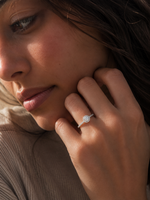 Load image into Gallery viewer, Lab-grown round halo diamond engagement ring with pavé side diamonds worn by a woman in a natural close-up portrait, showcasing a brilliant round center stone in white gold.