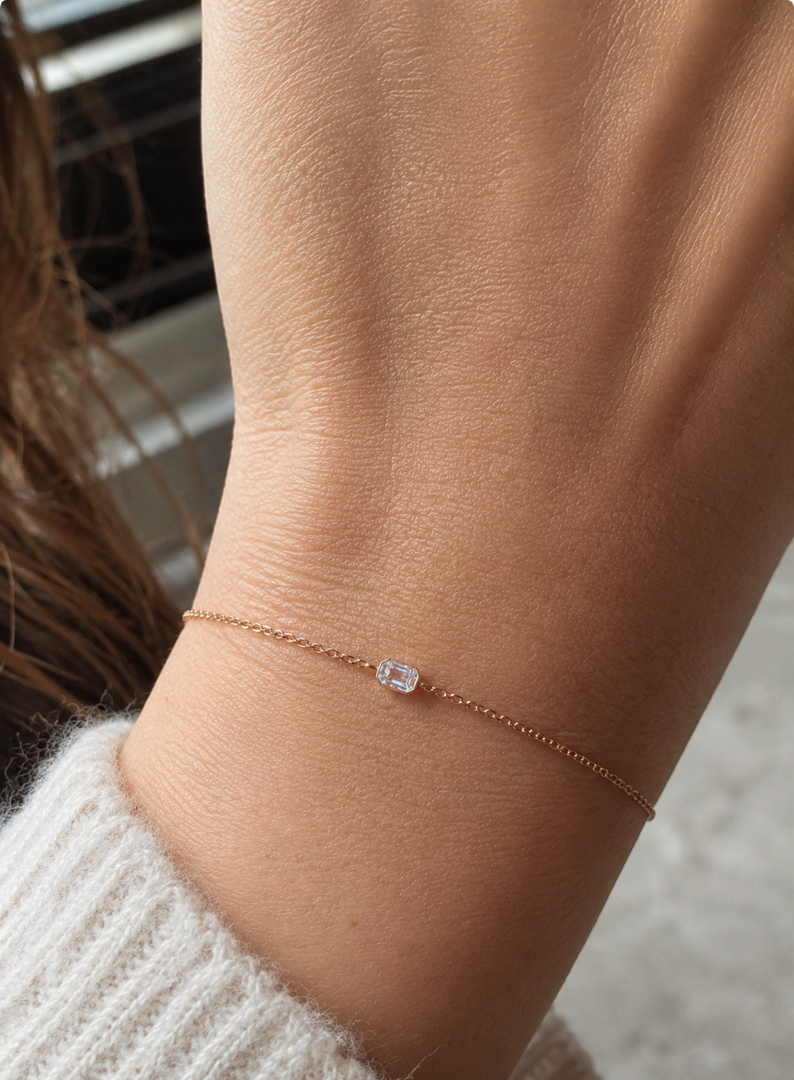     Emerald-cut natural diamond bezel bracelet worn on a woman’s wrist.