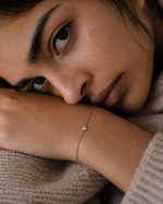 Load image into Gallery viewer, Woman resting her face on her arm while wearing a round bezel lab-grown diamond bracelet.