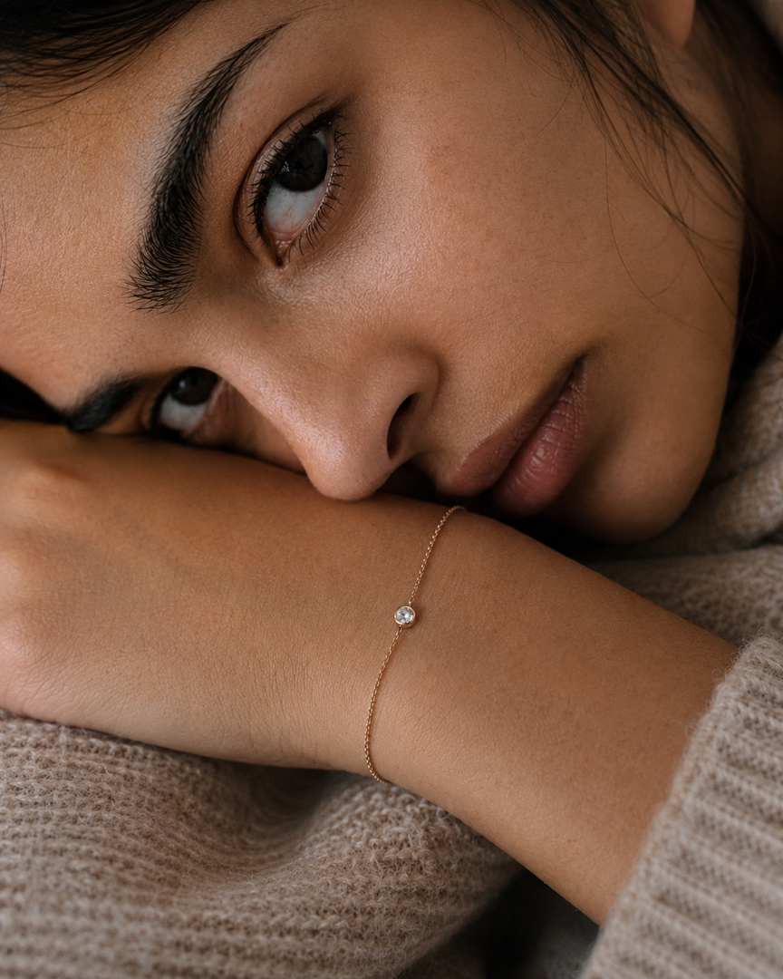 Woman resting her face on her arm while wearing a round bezel lab-grown diamond bracelet.